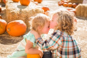 Sweet Little Boy Kisses His Baby Sister in a Rustic Ranch Setting at the Pumpkin Patch.
